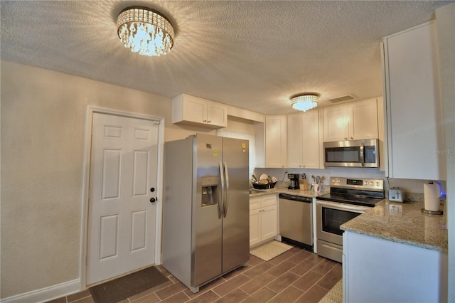 kitchen featuring stainless steel appliances, a textured ceiling, visible vents, and white cabinetry