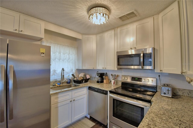 kitchen with visible vents, a textured ceiling, white cabinets, a sink, and stainless steel appliances