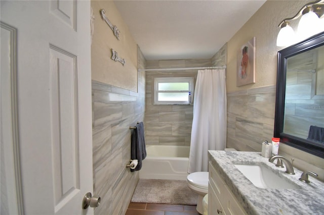 full bath featuring shower / bath combination with curtain, tile walls, tile patterned flooring, vanity, and toilet