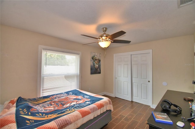 bedroom featuring a closet, visible vents, baseboards, ceiling fan, and dark wood-style floors
