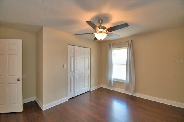 unfurnished bedroom with a closet, a ceiling fan, baseboards, and dark wood-style floors