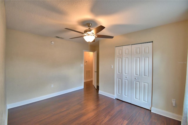 unfurnished bedroom featuring baseboards, visible vents, a closet, and dark wood-type flooring