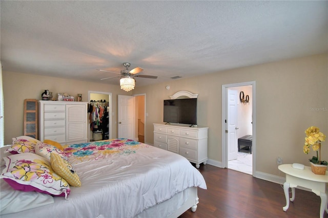 bedroom with a walk in closet, baseboards, dark wood-type flooring, visible vents, and a closet
