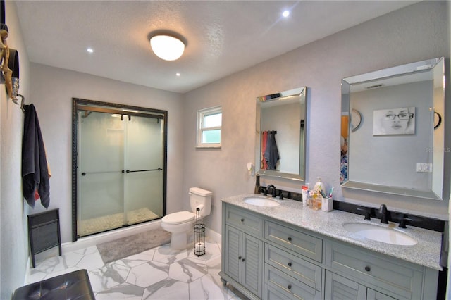bathroom with double vanity, a sink, a stall shower, and toilet