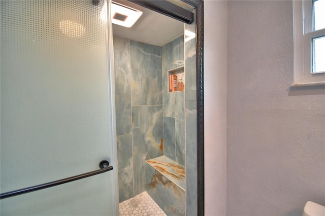 bathroom featuring a textured wall and walk in shower
