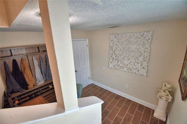 interior space with baseboards, a textured ceiling, and wood finished floors