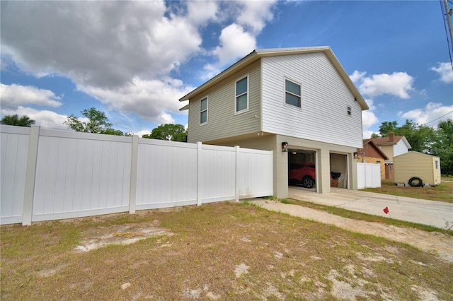 view of side of home with a garage, fence, and concrete driveway