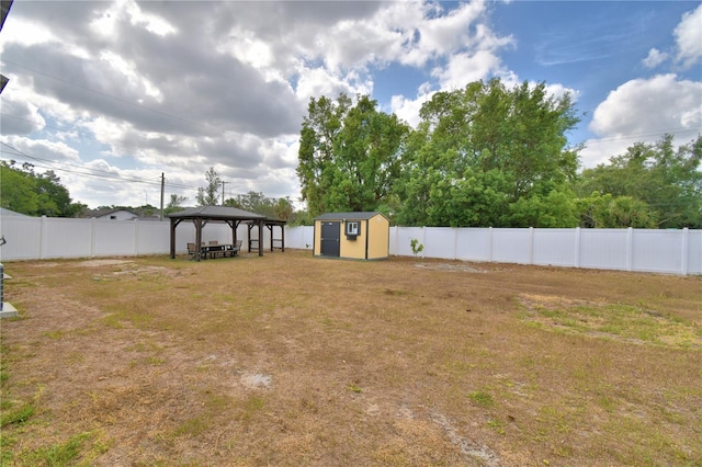 view of yard with a gazebo, an outdoor structure, a fenced backyard, and a storage unit