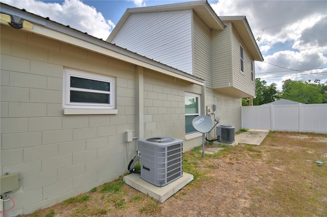 view of home's exterior featuring fence, central AC unit, and concrete block siding