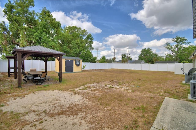 view of yard with a fenced backyard, a storage unit, an outbuilding, and a gazebo