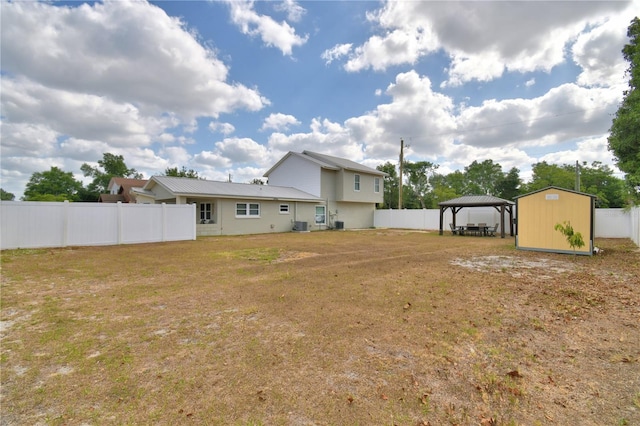 view of yard featuring central AC unit, a detached carport, fence, and an outbuilding