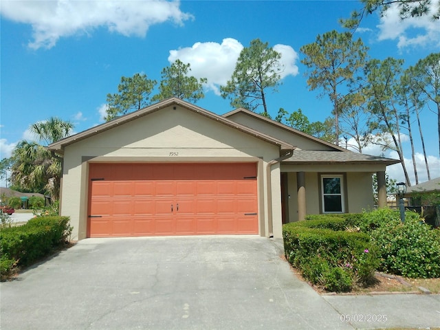 ranch-style home featuring concrete driveway, a garage, and stucco siding