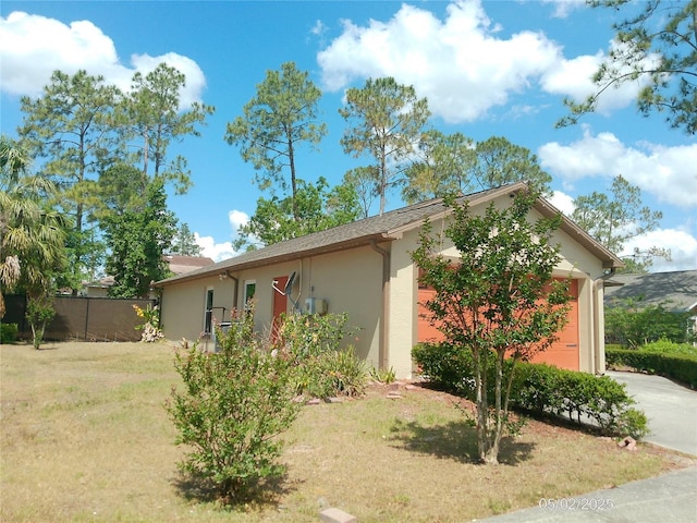 view of front of property with a front lawn, fence, stucco siding, concrete driveway, and an attached garage