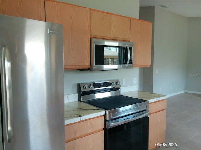 kitchen featuring light countertops, light brown cabinetry, and stainless steel appliances
