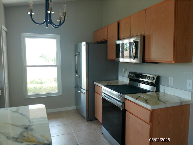 kitchen featuring baseboards, light countertops, appliances with stainless steel finishes, light tile patterned floors, and a notable chandelier