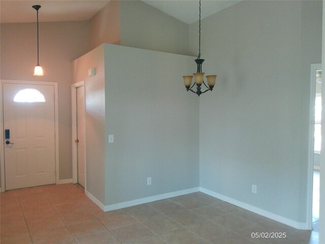 foyer featuring baseboards, a notable chandelier, light tile patterned floors, and a towering ceiling