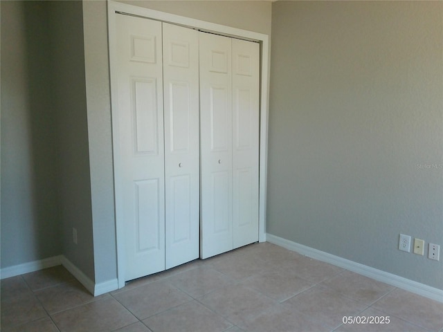 unfurnished bedroom with baseboards, light tile patterned floors, and a closet