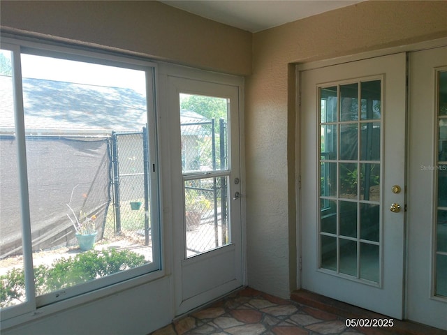doorway to outside with a textured wall and plenty of natural light