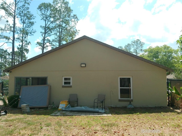 view of side of property featuring a patio area, stucco siding, and a yard
