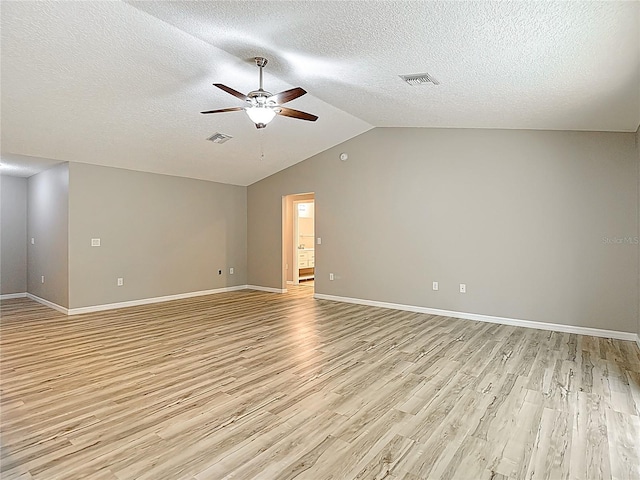 empty room with a ceiling fan, light wood-type flooring, baseboards, a textured ceiling, and vaulted ceiling