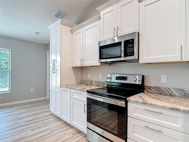 kitchen with stainless steel appliances, white cabinetry, light wood finished floors, light stone counters, and a textured ceiling