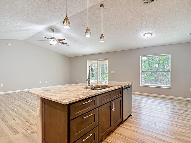 kitchen featuring a sink, stainless steel dishwasher, open floor plan, light wood finished floors, and a textured ceiling