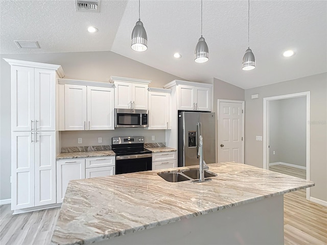 kitchen with stainless steel appliances, vaulted ceiling, light wood finished floors, white cabinetry, and a sink