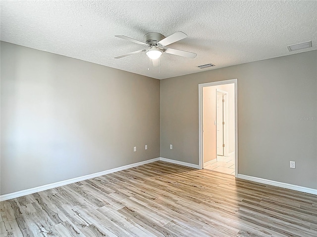 spare room with light wood-style flooring, a ceiling fan, a textured ceiling, and baseboards