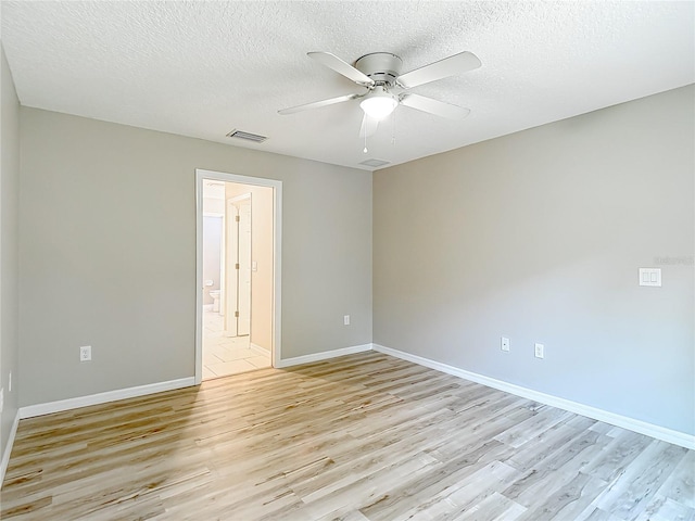 empty room featuring light wood-type flooring, ceiling fan, a textured ceiling, and baseboards
