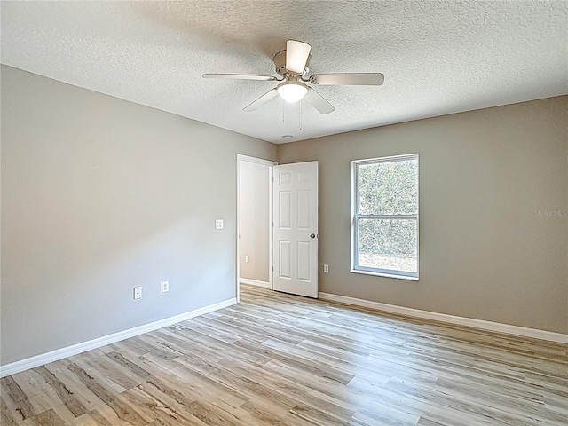 empty room featuring light wood finished floors, ceiling fan, baseboards, and a textured ceiling