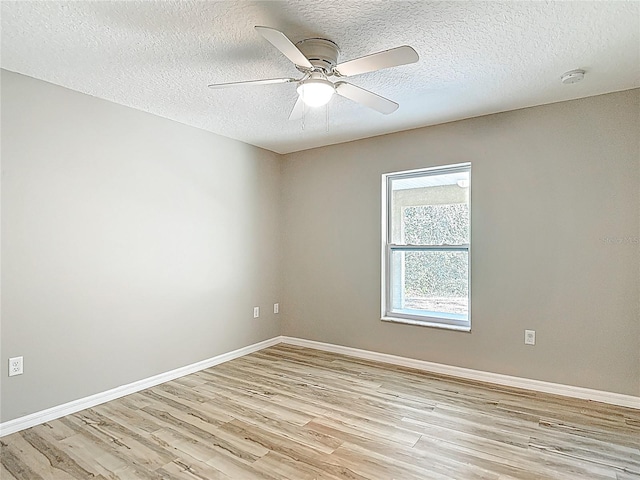 spare room with light wood finished floors, a textured ceiling, ceiling fan, and baseboards