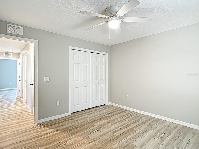 unfurnished bedroom featuring light wood-style floors, baseboards, a closet, a textured ceiling, and ceiling fan