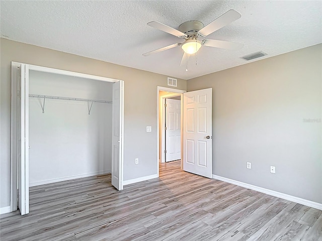unfurnished bedroom featuring wood finished floors, baseboards, a closet, a textured ceiling, and a ceiling fan