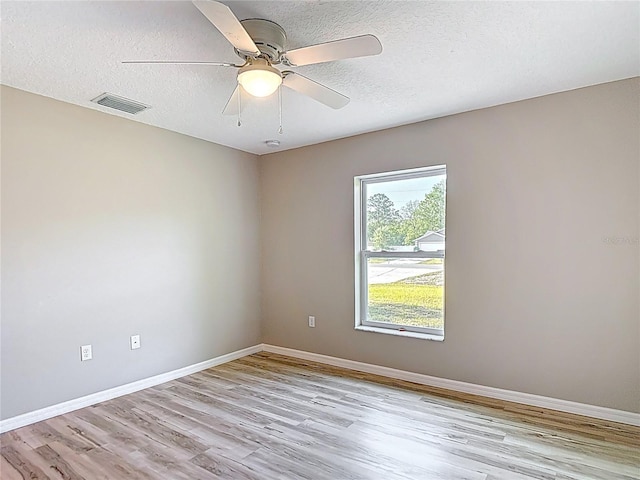 empty room featuring light wood-style flooring, baseboards, a textured ceiling, and a ceiling fan
