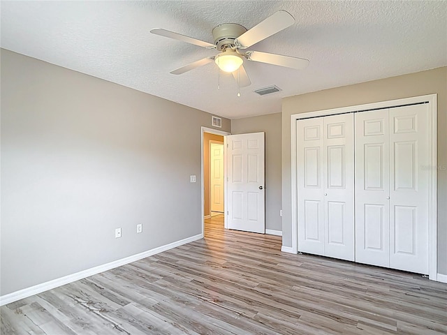 unfurnished bedroom with light wood-style floors, baseboards, a closet, a textured ceiling, and ceiling fan
