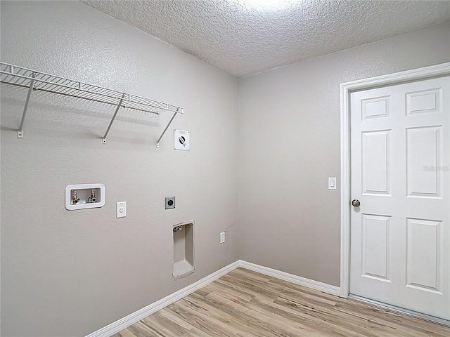 laundry area featuring hookup for an electric dryer, light wood finished floors, washer hookup, a textured ceiling, and baseboards