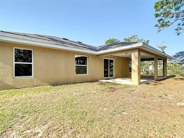 back of property featuring stucco siding, a patio, and a yard