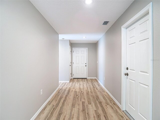 hallway featuring light wood-style floors, baseboards, and recessed lighting