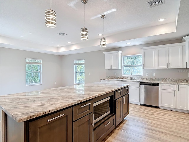 kitchen with appliances with stainless steel finishes, a raised ceiling, light wood-style flooring, white cabinets, and recessed lighting