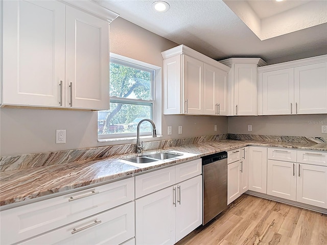 kitchen featuring dishwasher, a sink, white cabinetry, light wood-style floors, and light stone countertops