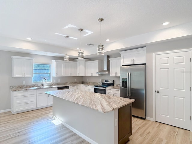 kitchen featuring appliances with stainless steel finishes, wall chimney range hood, a center island, light wood-style flooring, and white cabinets