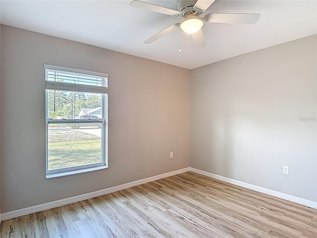 spare room featuring light wood finished floors, baseboards, and a ceiling fan