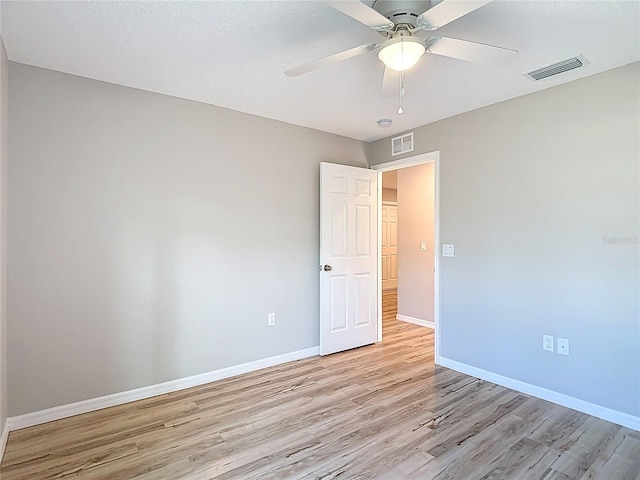 spare room with light wood-style floors, ceiling fan, and baseboards