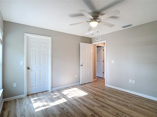 unfurnished bedroom featuring wood finished floors, baseboards, ceiling fan, and a textured ceiling