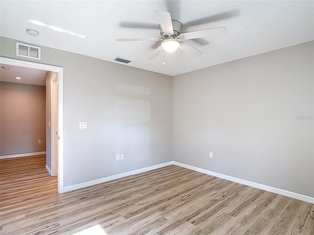 empty room featuring light wood-style floors, a ceiling fan, and baseboards