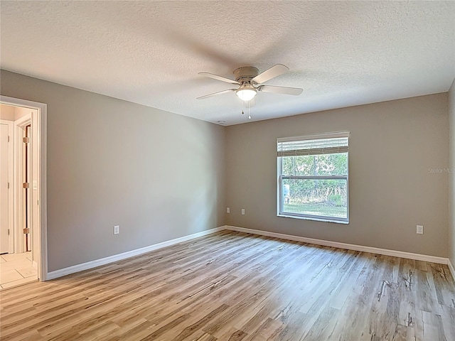 spare room with light wood-style flooring, ceiling fan, baseboards, and a textured ceiling