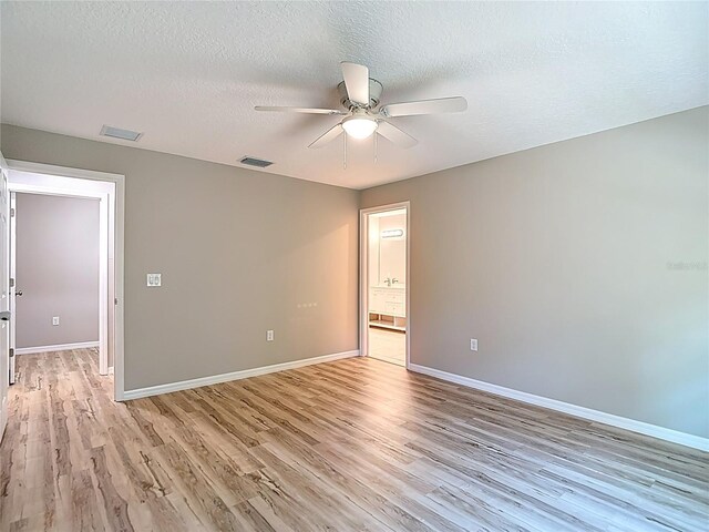 empty room with ceiling fan, light wood-type flooring, baseboards, and a textured ceiling