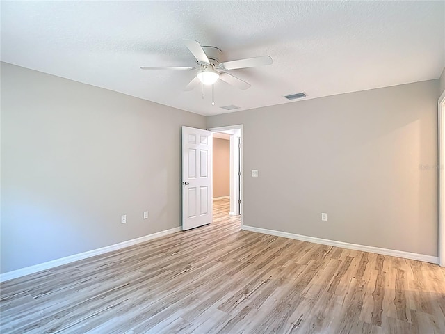 unfurnished room with light wood-style floors, ceiling fan, baseboards, and a textured ceiling