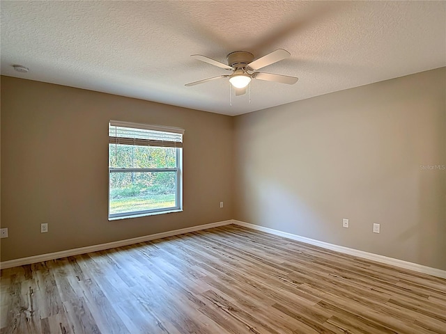 spare room with light wood finished floors, a ceiling fan, baseboards, a textured ceiling, and a smoke detector