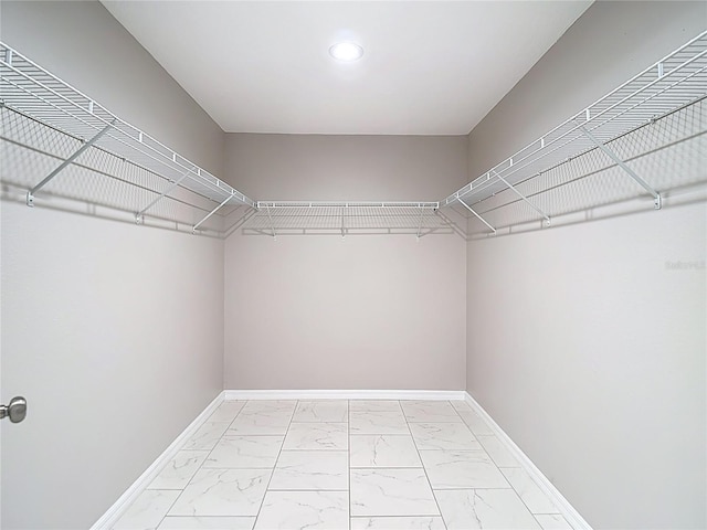 walk in closet featuring light marble finish floors